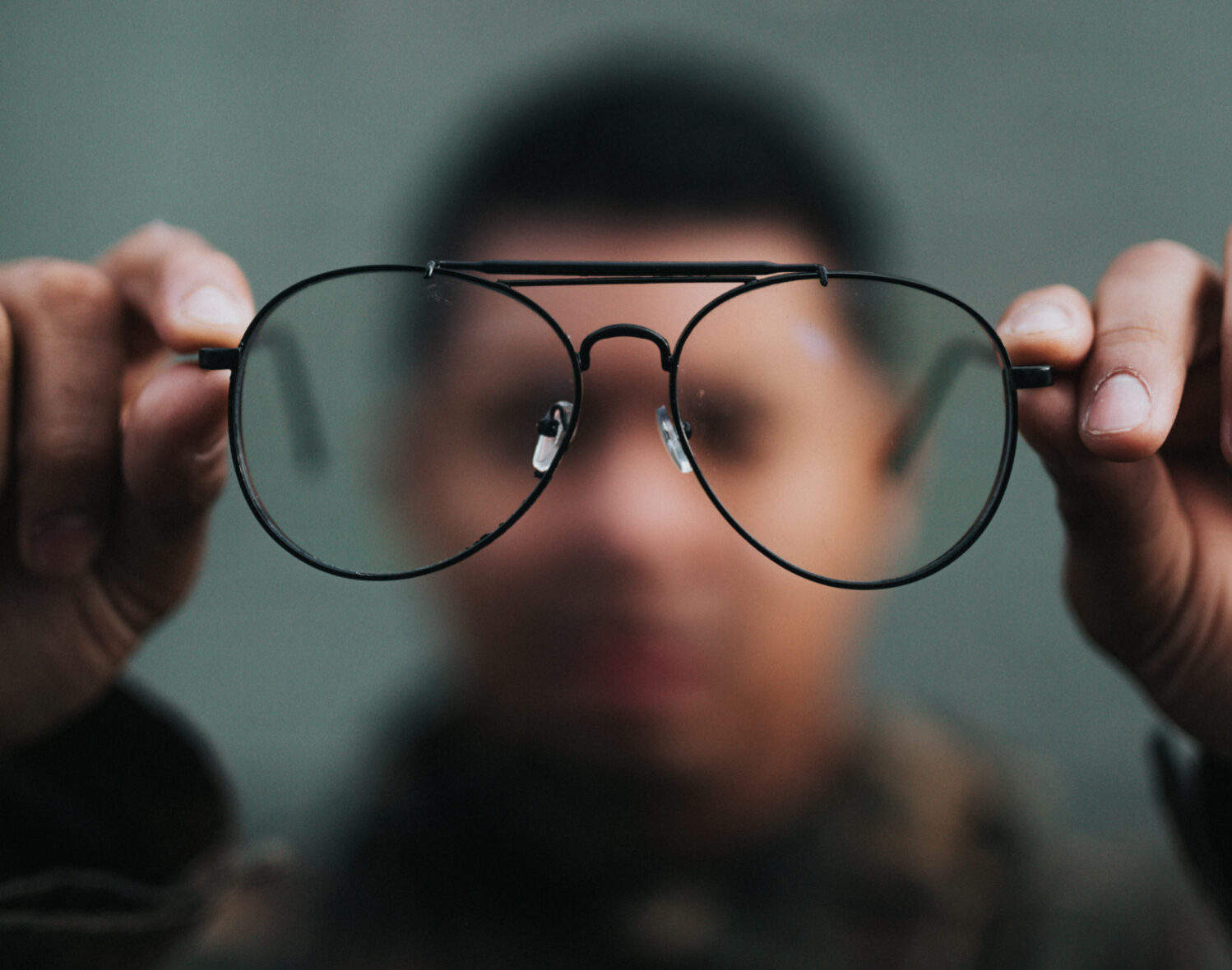 Man holding glasses out trying to get a closer look, blurry